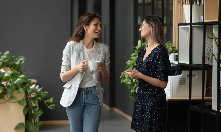 two women co-workers laughing and talking in office
