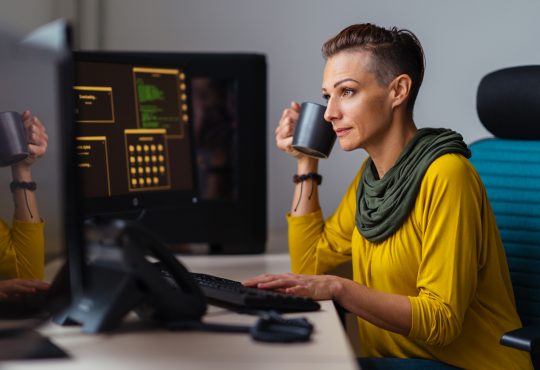 Businesswoman wearing yellow shirt working in the office and drinking coffee