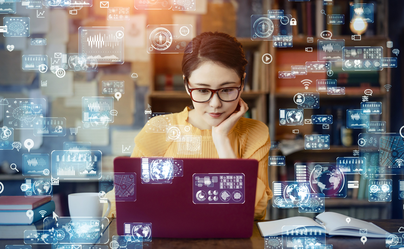 photo illustration of woman sitting at laptop with translucent technology symbols floating around her