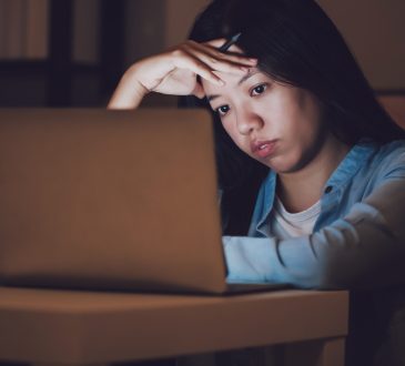 woman working at night on laptop looking stressed