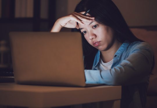 woman working at night on laptop looking stressed