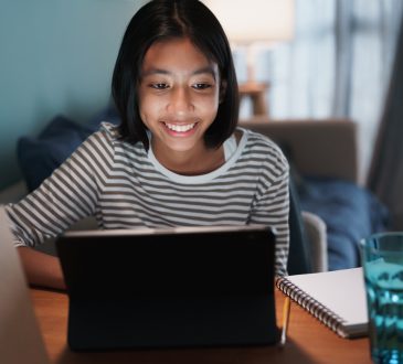 teen girl smiling while looking at tablet