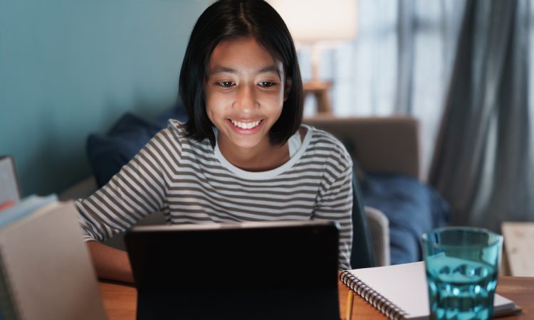 teen girl smiling while looking at tablet