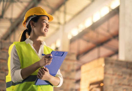 female engineer inspector wearing hard hat and holding clipboard