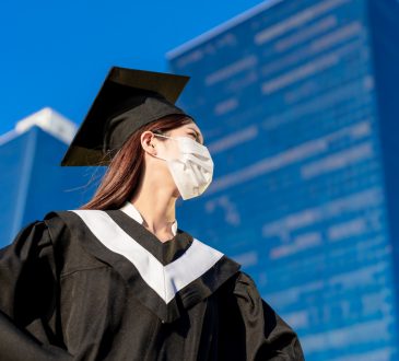 female student wearing graduation gown and mask