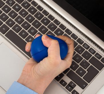hand squeezing stress ball over laptop keyboard