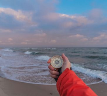 First-person view of a female hand with a compass on a background of ocean