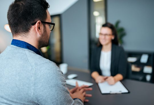 Young male worker being interviewed for a job by a women.