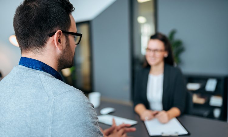 Young male worker being interviewed for a job by a women.