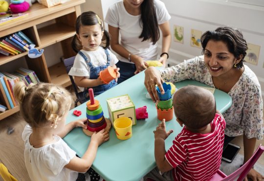 Nursery children playing with teacher in the classroom