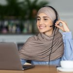 woman wearing headset and smiling at laptop screen