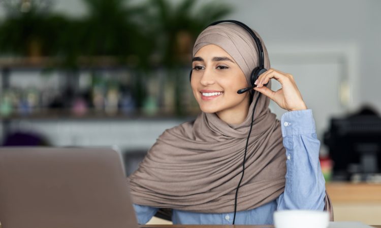 woman wearing headset and smiling at laptop screen
