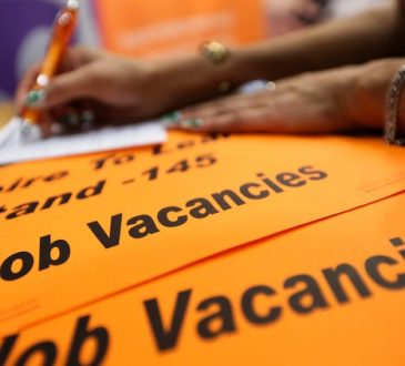 person writing on top of orange papers showing job vacancies