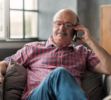 man talking on phone sitting at living room.