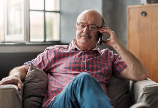 man talking on phone sitting at living room.