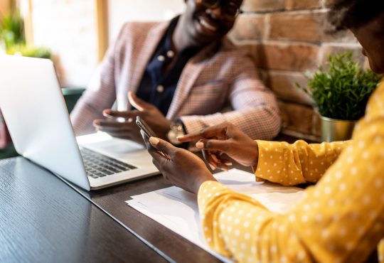 man and woman looking at laptop in cafe