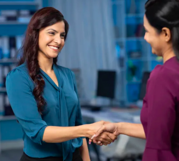 two women shaking hands in office