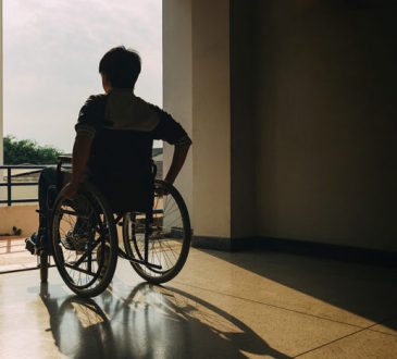 person in wheelchair looking out window