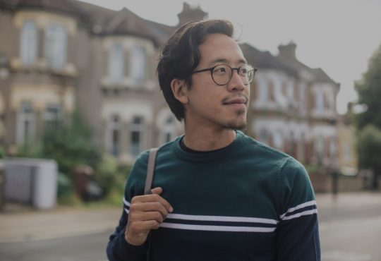 pensive male college student walking in residential area