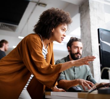 woman and man working together at computer in office