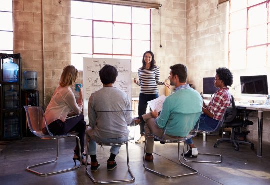 Group of people watching woman present in office