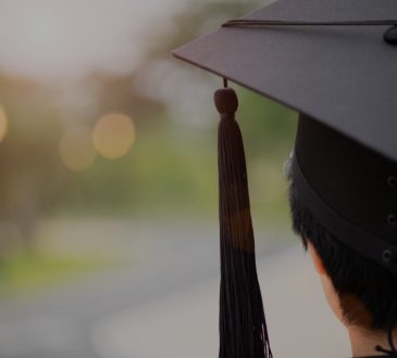 closeup rear view of student with short black hair wearing graduation cap
