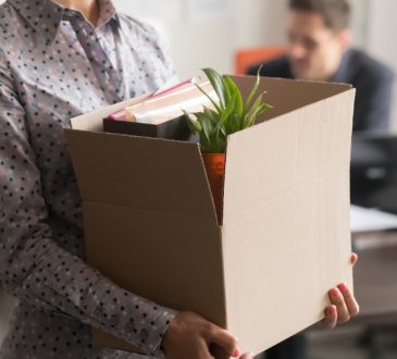 Closeup of woman holding cardbox box with office belongings.