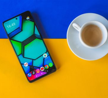 Phone and coffee pictured from above on bright blue and yellow background.