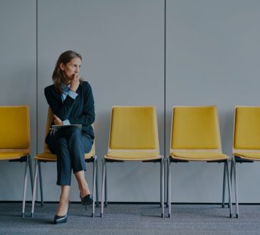 Woman sitting in yellow chair in interview waiting room.