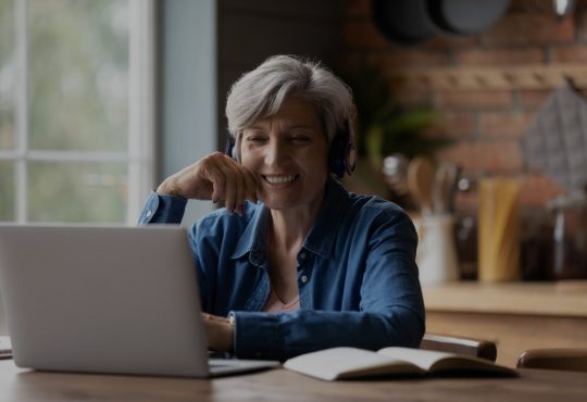 Older woman watching something on laptop screen at home.