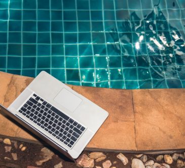 Laptop sitting near edge of pool.