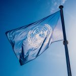 UN flag against blue sky.