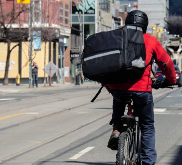 Bicycle food delivery person biking down street.
