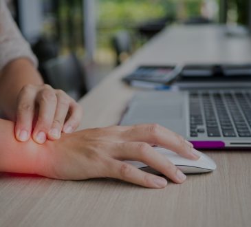 Closeup of woman holding wrist in pain while working at computer