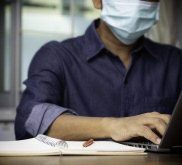 Man sitting at desk wearing face mask.