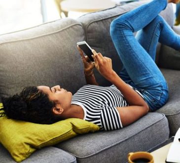 Woman lying on couch looking at phone