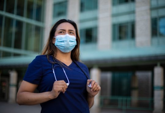 Health care worker standing in front of hospital.