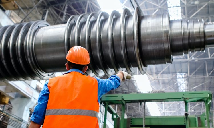Worker in manufacturing plant wearing orange safety vest and hard hat