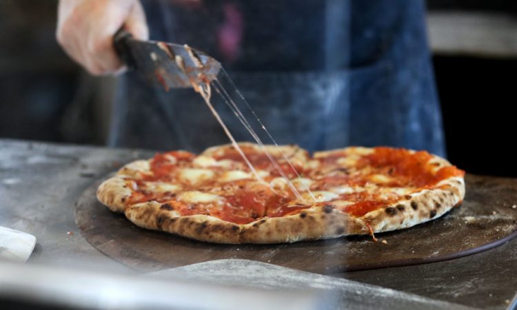 Person cutting pizza with knife