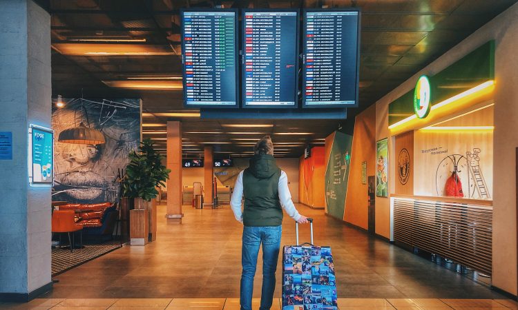 Woman with suitcase looking at flights screen in airport