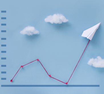 Conceptual origami paper plane pulling business finance growth chart line flying upwards on blue sky background.