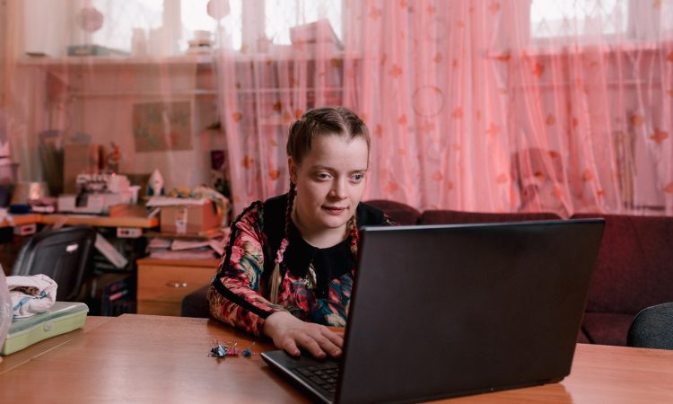 Young woman typing on laptop in bedroom.