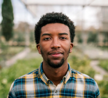 Young man standing in front of greenery outdoors