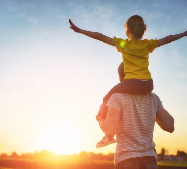 Dad walking outside with daughter on shoulders