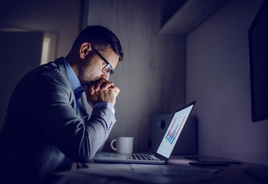 Stressed man working on laptop at night