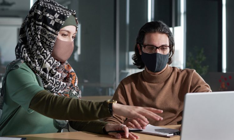 Man and woman wearing masks and looking at computer
