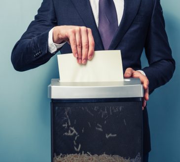 Person in suit shredding document