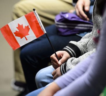 Person sitting in waiting area holding small Canadian flag