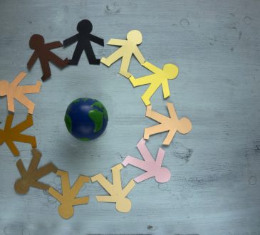 Paper cutouts of people in different colours in circle around small globe