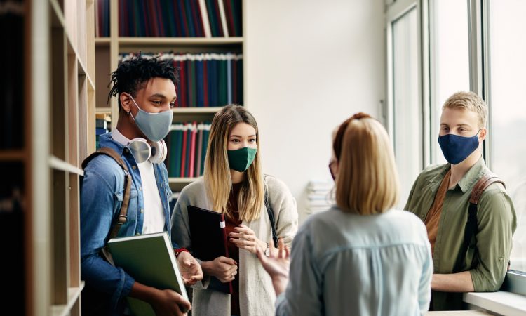 College students wearing masks and talking in library
